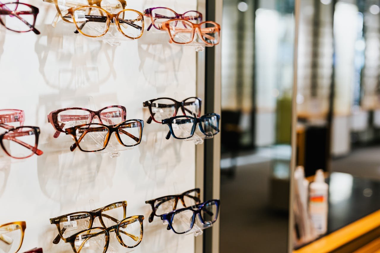 Assorted eyeglasses on a well-lit shelf in an opticians store.